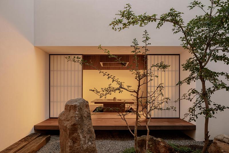 גן אבנים יפני בתוך בית פרטי במקסיקו, חלל מרכזי פתוח עם חצץ אפור ופלטפורמות עץ – אדריכלות זן